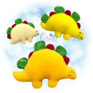 Puede incluir: Tres juguetes de peluche de dinosaurio con caras sonrientes. Los dinosaurios son de color amarillo y crema con detalles verdes y rojos. Los dinosaurios son de diferentes tamaños.