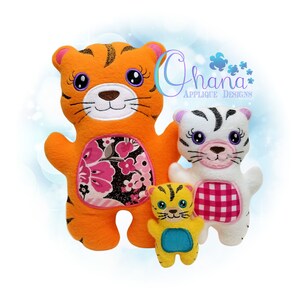 Könnte beinhalten: Drei Plüschtiger in verschiedenen Größen. Der größte Tiger ist orange mit schwarzen Streifen und einem Stoffpatch mit Blumenmuster auf dem Bauch. Der mittlere Tiger ist weiß mit schwarzen Streifen und einem roten und weißen karierten Stoffpatch auf dem Bauch. Der kleinste Tiger ist gelb mit schwarzen Streifen und einem blauen Stoffpatch auf dem Bauch. Alle drei Tiger haben gestickte Gesichter mit rosa Nasen und lila Augen.