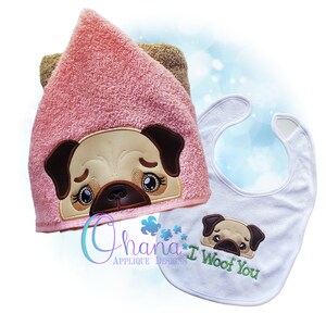 May include: A pink hooded towel with an embroidered pug face and a white bib with an embroidered pug face and the text "I Woof You".