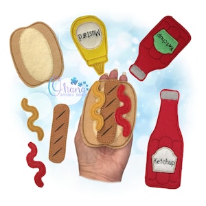 May include: Felt craft set for a hot dog, with a bun, sausage, mustard, and ketchup. The set includes two bottles of ketchup, one with a green label and the other with a white label.