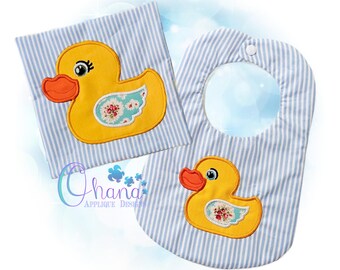 May include: A baby bib and burp cloth set with a yellow duck applique. The duck has an orange beak and a floral wing design. The bib and burp cloth have a blue and white striped pattern.