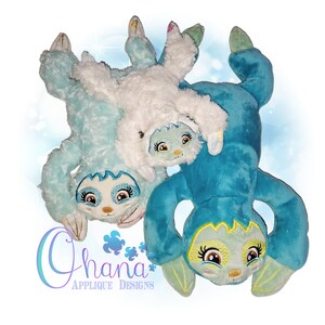 May include: Two plush blue and white sloths with embroidered faces and details. The sloths are in a playful pose, with one on top of the other. The image includes the text "Chana Applique Designs".