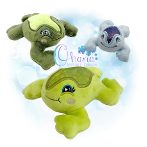 Puede incluir: Tres juguetes de peluche con forma de tortuga en tonos verdes y azules. Las tortugas tienen caras sonrientes, ojos bordados y cuerpos suaves y texturizados. El texto "Ohana Applique Designs" es visible en la imagen.