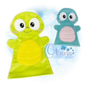 May include: Two plush hand puppets. One is lime green with a yellow belly and the other is light blue with a pink belly. Both have large eyes, small smiles, and are designed to look like friendly creatures. The text "Ohana Applique Designs" is visible.