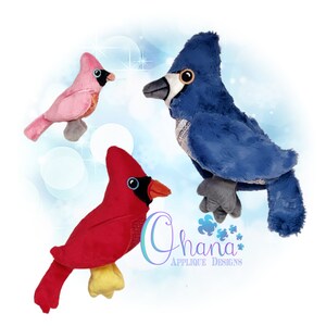 May include: Three plush toy birds: a red cardinal, a blue jay, and a pink bird. The birds are all sitting on a white background with a blue and white swirl pattern.