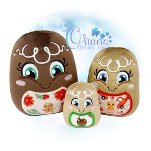 May include: Three plush gingerbread-themed toys with embroidered faces and decorative details. The largest is brown, the middle is tan, and the smallest is tan. The toys have smiling faces, and the largest has a floral pattern.