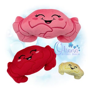 Pode incluir: Três brinquedos de pelúcia em forma de caranguejo com rostos sorridentes. Os caranguejos são rosa, vermelho e amarelo.