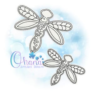 May include: Two white dragonfly applique designs with black embroidered details. The dragonflies have detailed wings and decorative swirls on their bodies. The background is a soft blue with bokeh effects and the text "Ohana Applique Designs".