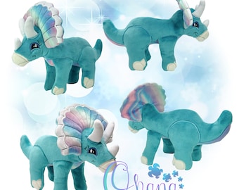 May include: A plush turquoise triceratops toy with iridescent rainbow scales on its frill. The toy is shown in four different poses, including standing, walking, and looking down. The toy is made by Ohana Applique Designs.