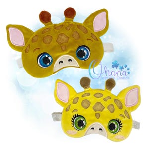 May include: Two yellow giraffe-shaped sleep masks with brown spots, ears, and horns. The masks have large, embroidered eyes with blue and green irises, and a white elastic band. The text "Ohana Applique Designs" is visible.