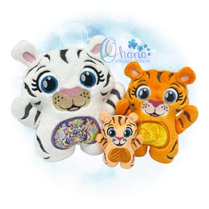 Könnte beinhalten: Drei Plüschtiger, ein weißer, ein orangefarbener und ein kleinerer orangefarbener. Der weiße Tiger hat ein buntes Tigerdesign auf seinem Bauch. Die orangefarbenen Tiger haben ein gelbes Design auf ihrem Bauch. Die Spielzeuge haben gestickte Augen und Nasen.