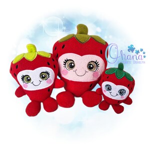 May include: Three plush strawberry toys in varying sizes. Each has a red body, green leafy top, and a smiling face with eyelashes and rosy cheeks. The largest strawberry has a white stripe across the middle.