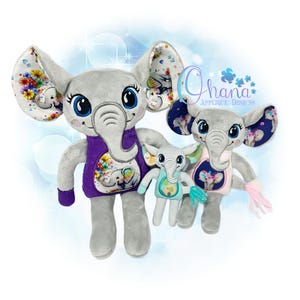 Op de afbeelding: Drie pluche olifanten met geborduurde details. De grootste olifant draagt een paars shirt met een bloemenpatroon en een kleinere olifant op de voorkant. De middelste olifant draagt een roze shirt met een bloemenpatroon en een kleinere olifant op de voorkant. De kleinste olifant draagt een blauw shirt met een bloemenpatroon en een kleinere olifant op de voorkant. De tekst "Ohana Applique Designs" is zichtbaar op de achtergrond.