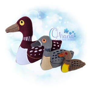 May include: Three plush duck toys in varying sizes. The largest duck is burgundy with white accents, a brown beak, and a yellow eye. The middle duck is gray with a tan chest and a brown beak. The smallest duck is brown with a yellow chest.