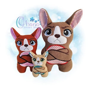 Può includere: Tre figure di cani di peluche di varie dimensioni. I cani sono marroni, beige e marrone-rossiccio con facce bianche e grandi occhi espressivi. Le orecchie sono foderate con un motivo a pois. Il testo "Ohana Applique Designs" si trova nell'angolo in alto a sinistra.