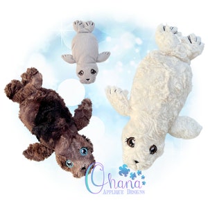 May include: Three plush toy seals in different colors: brown, gray, and white. Each seal has embroidered eyes and a cute expression. The seals are lying on a blue background with white sparkles.