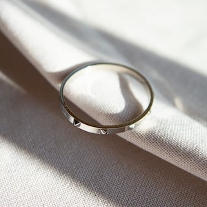 May include: A silver bangle bracelet with small, triangular accents around the circumference.