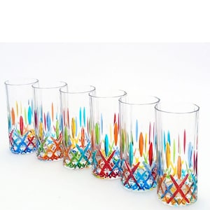 Könnte beinhalten: Ein Set aus sechs klaren Trinkgläsern mit einem lebendigen, mehrfarbig bemalten Muster am Boden. Das Design besteht aus sich kreuzenden Linien und vertikalen Strichen in Rot, Blau, Grün, Orange und Gelb, die einen farbenfrohen Effekt erzeugen.