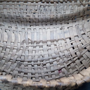 May include: A woven basket made of natural materials, with a light brown color and a slightly curved shape. The basket is made with a tight weave and has a smooth, even surface.