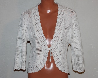 May include: White crocheted cardigan with a tie front and a scalloped neckline.