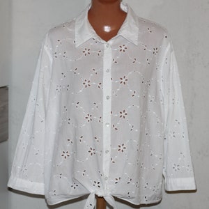 May include: White eyelet blouse with a button-up front and a tie at the bottom.