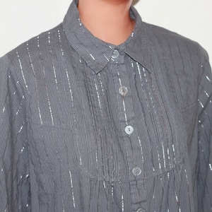 May include: A gray and silver striped long-sleeved button-down shirt.
