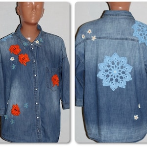 May include: A blue denim shirt with orange and white crocheted flowers and a blue crocheted snowflake on the back.