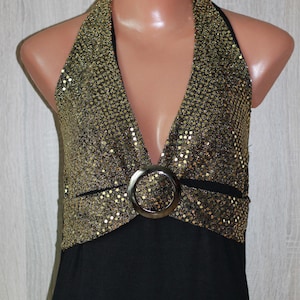 Puede incluir: Un vestido negro de tirantes con la parte superior de lentejuelas doradas y un acento de hebilla plateada.