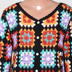 May include: A black crochet cardigan with colorful square patterns in red, orange, yellow, green, blue, purple, and white. The cardigan has a button closure.