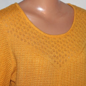 Peut inclure: Un pull jaune moutarde avec un délicat motif ajouré autour de l'encolure.