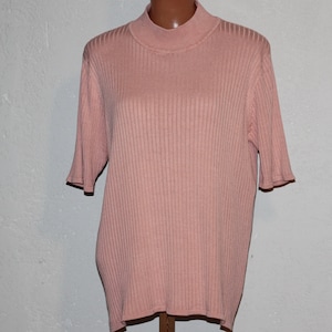 May include: A pink ribbed knit top with a mock neck and short sleeves.