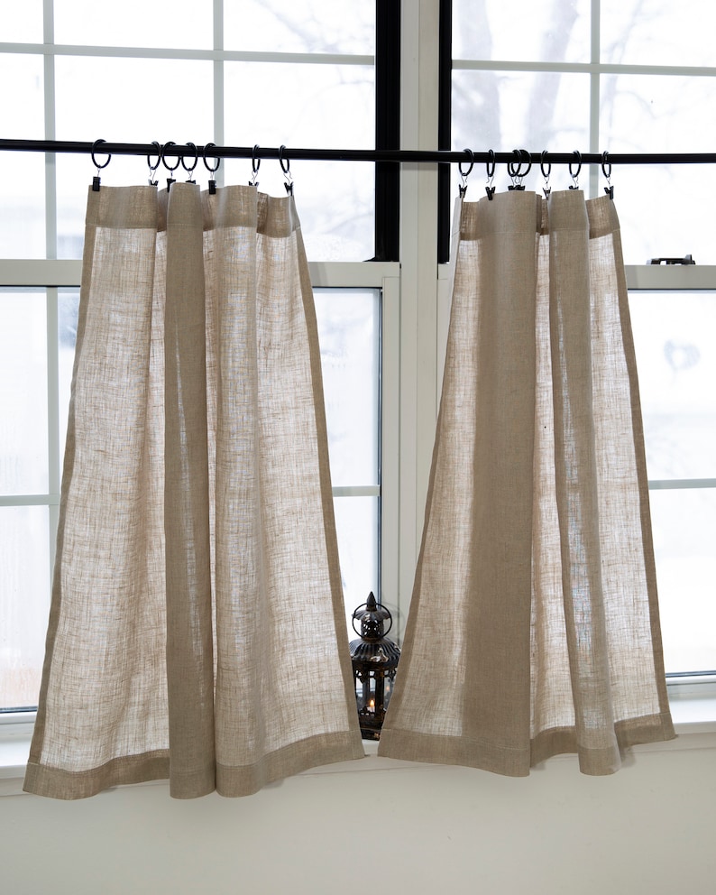 Puede incluir: Dos pares de cortinas de caf&eacute; de lino beige colgadas de una barra de cortina negra. Las cortinas est&aacute;n fruncidas en la parte superior y tienen un estilo sencillo y casual.