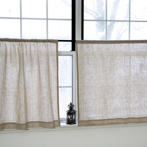 Puede incluir: Dos cortinas de caf&eacute; de lino beige cuelgan de una barra de cortina negra frente a una ventana. Una peque&ntilde;a linterna de metal negro se encuentra en el alf&eacute;izar de la ventana.
