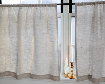 May include: Two white linen cafe curtains with a brown trim hang in a window. Three candles are on the windowsill.