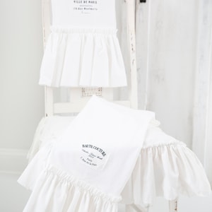 May include: Two white kitchen towels with ruffled edges. The top towel has the text "VILLE DE PARIS" and the bottom towel has the text "HAUTE COUTURE."