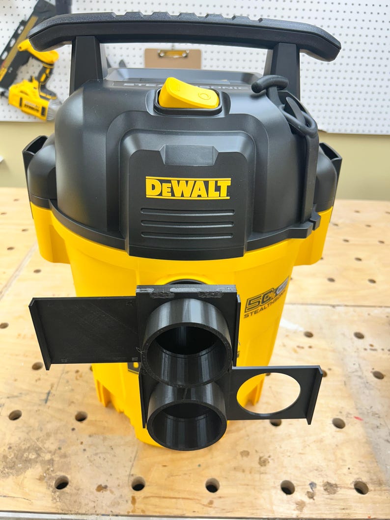 May include: A yellow and black DEWALT wet/dry vacuum with a black handle and a yellow button. The vacuum has a black attachment with two circular openings and a circular hole. The DEWALT logo is prominently displayed on the front.