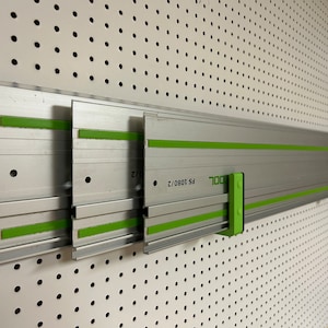 May include: Three silver and green aluminum track systems for a pegboard wall. The track systems are labeled "TOOL" and "FS 1090/2".
