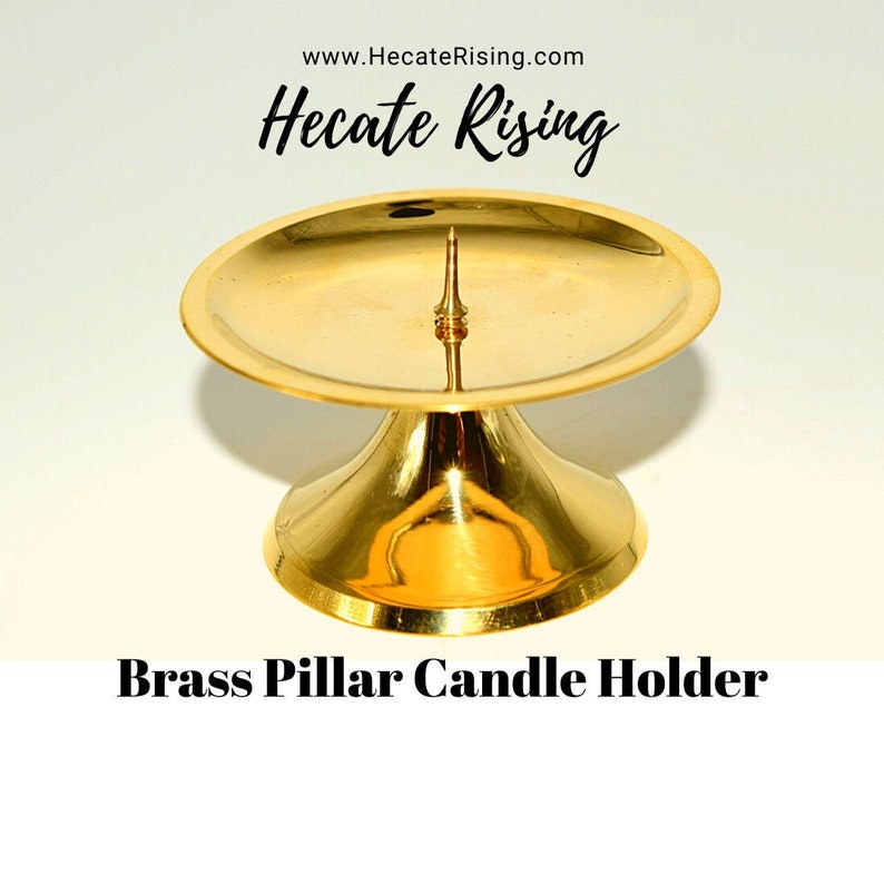 May include: A gold brass pillar candle holder with a round base and a small spike on top.