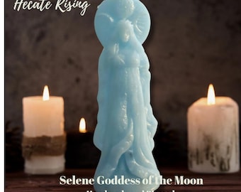 Puede incluir: Una vela de pilar azul claro con forma de figura de pie con un halo circular detrás de la cabeza, con el texto Hecate Rising, www.HecateRising.com, Selene Goddess of the Moon y Handmade and Blessed Altar Candle.