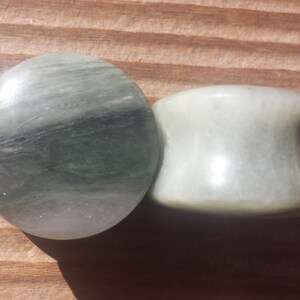 May include: Two green and white stone ear gauges. The larger gauge is a cylinder shape and the smaller gauge is a flat disc.