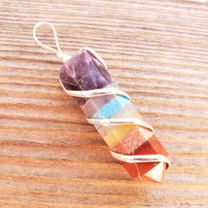 Peut inclure: Un pendentif en cristal à sept chakras enroulé d'un fil d'argent. Le pendentif est composé de sept pierres de couleurs différentes, dont l'améthyste, le quartz clair, la turquoise bleue, la citrine jaune, la cornaline orange, le jaspe rouge et une base rouge.
