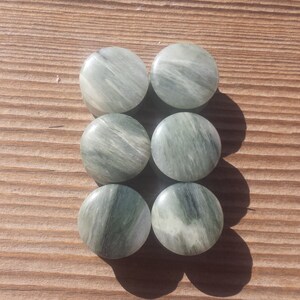 May include: Six round green and white agate stone cabochons. The stones have a swirling pattern and are smooth and polished.