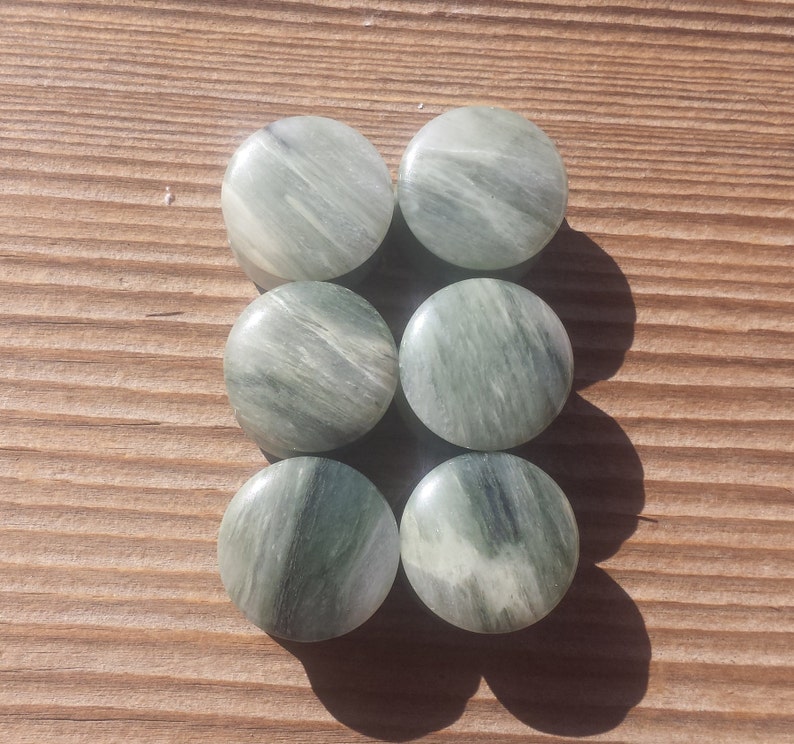May include: Six round green and white agate stone cabochons. The stones have a swirling pattern and are smooth and polished.