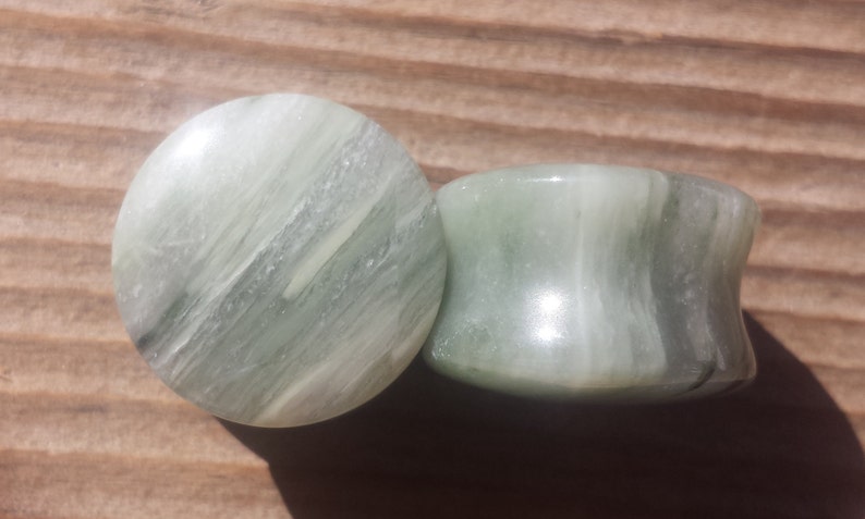 May include: Two green and white striped stone ear gauges. The gauges are round and have a smooth, polished finish.