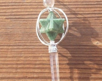 Op de afbeelding: Een zilveren slinger met een groene stervormige kristal en een heldere kwartspunt. De slinger hangt aan een zilveren ketting.