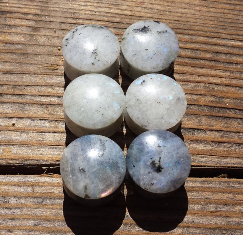 May include: Six round, white and blue gemstone plugs. The plugs are made of natural stone and have a speckled appearance.