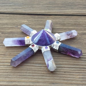 May include: Amethyst crystal grid with seven points, a purple pyramid in the center, and silver accents. Each point has a small colored stone.