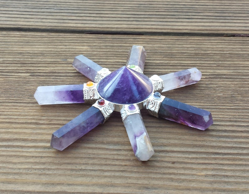 May include: Amethyst crystal grid with seven points, a purple pyramid in the center, and silver accents. Each point has a small colored stone.