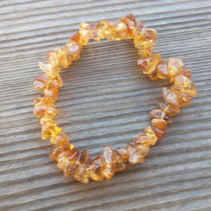 Pode incluir: Um bracelete feito de pequenas peças irregulares de pedras de citrino de cor laranja-marrom.