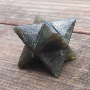 May include: A dark green labradorite star shaped crystal with iridescent blue and green hues.
